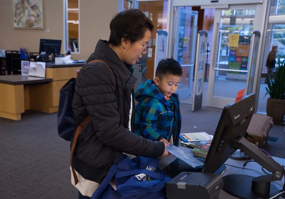 Family at self-checkout station at the Southwest Branch