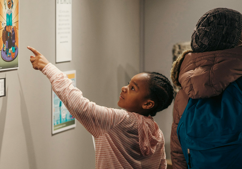 A child views Summer of Learning art work at the 2022 Art Exhibit opening at the Central Library.