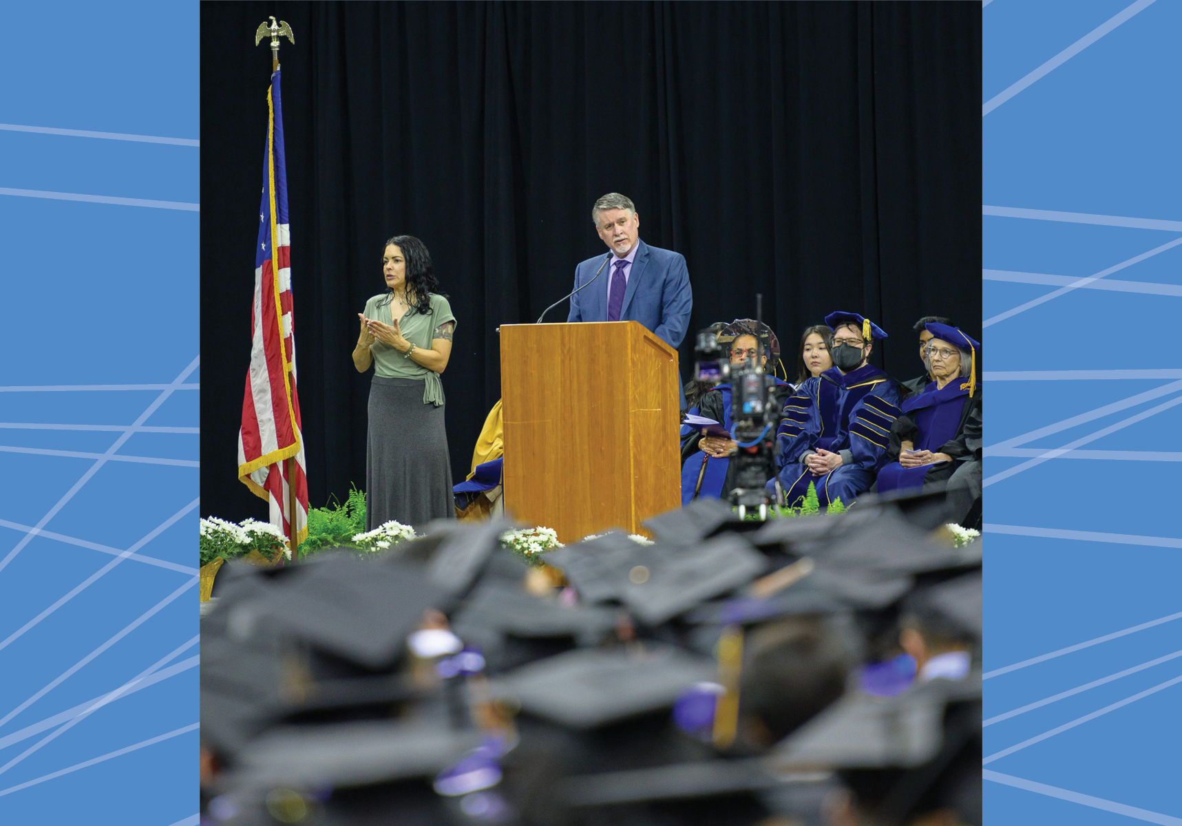 Tom Fay speaking at a podium in front of graduates.